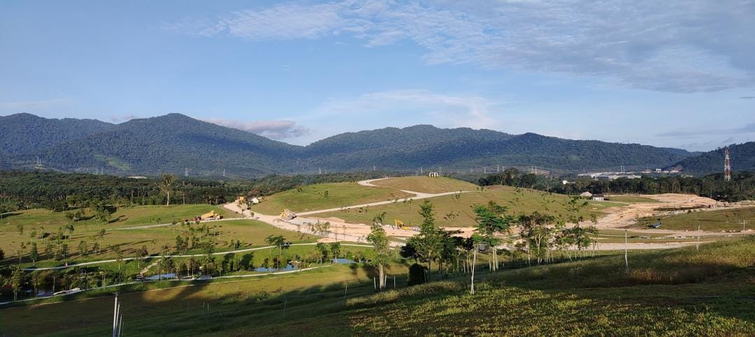 Forest-covered hills beyond the open sloping land and roads at Anyara Hills